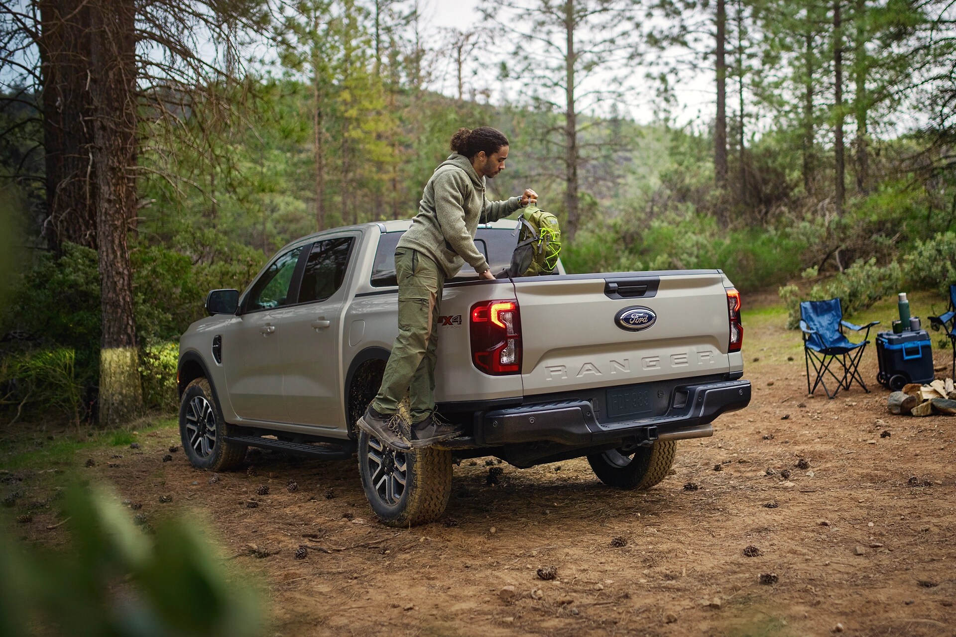 A man is stepping on the side-step to put gear into the bed of a 2025 Ford Ranger®