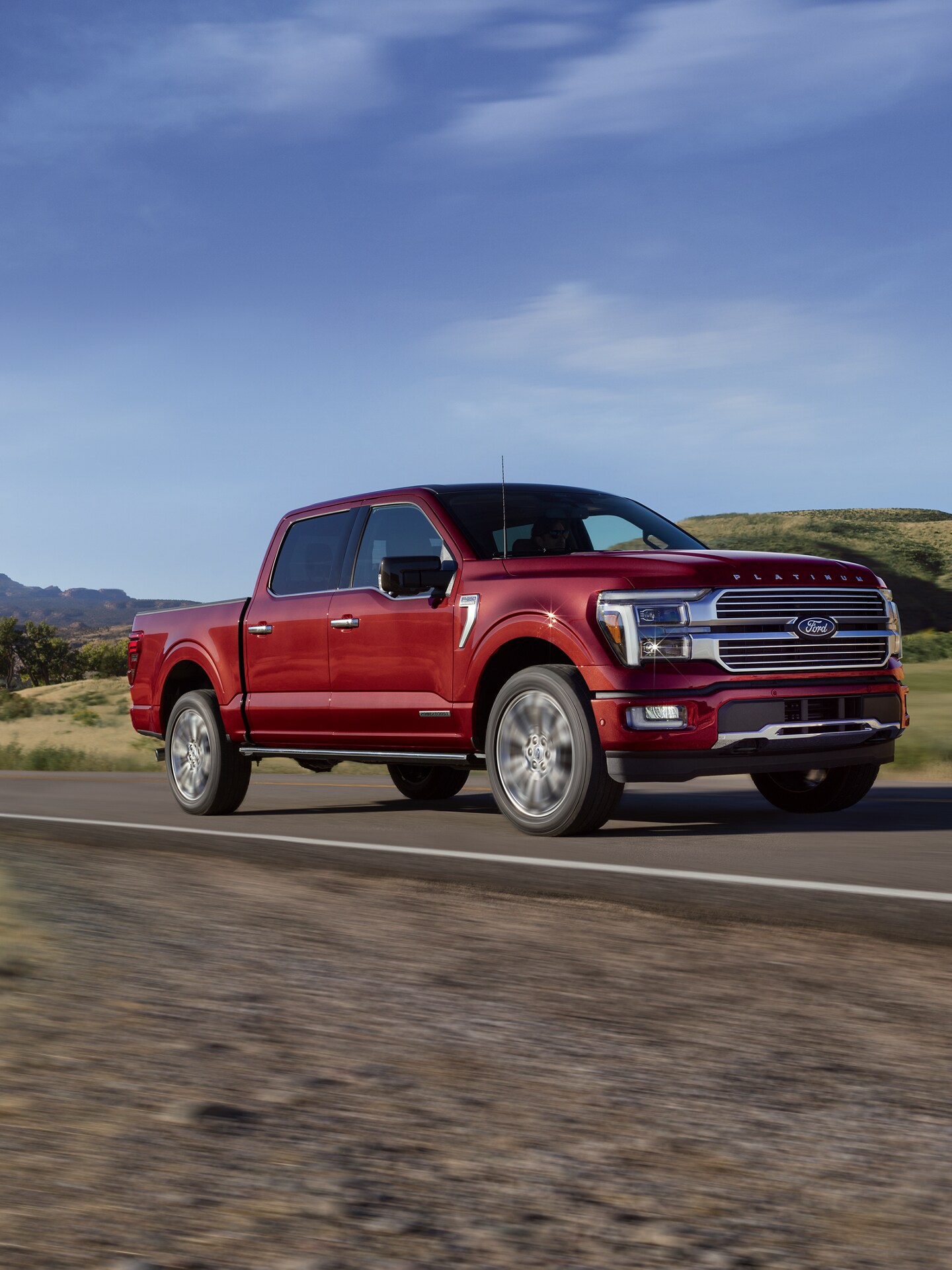 A 2025 Ford F-150® accelerates on a paved hillside road at sunrise