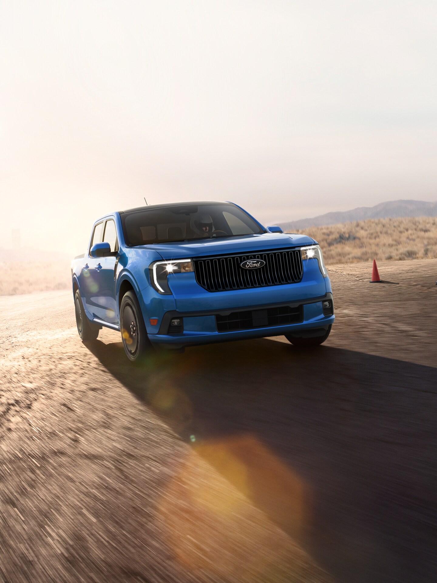 A 2025 Ford Maverick® accelerates up a mountainside road at sunset