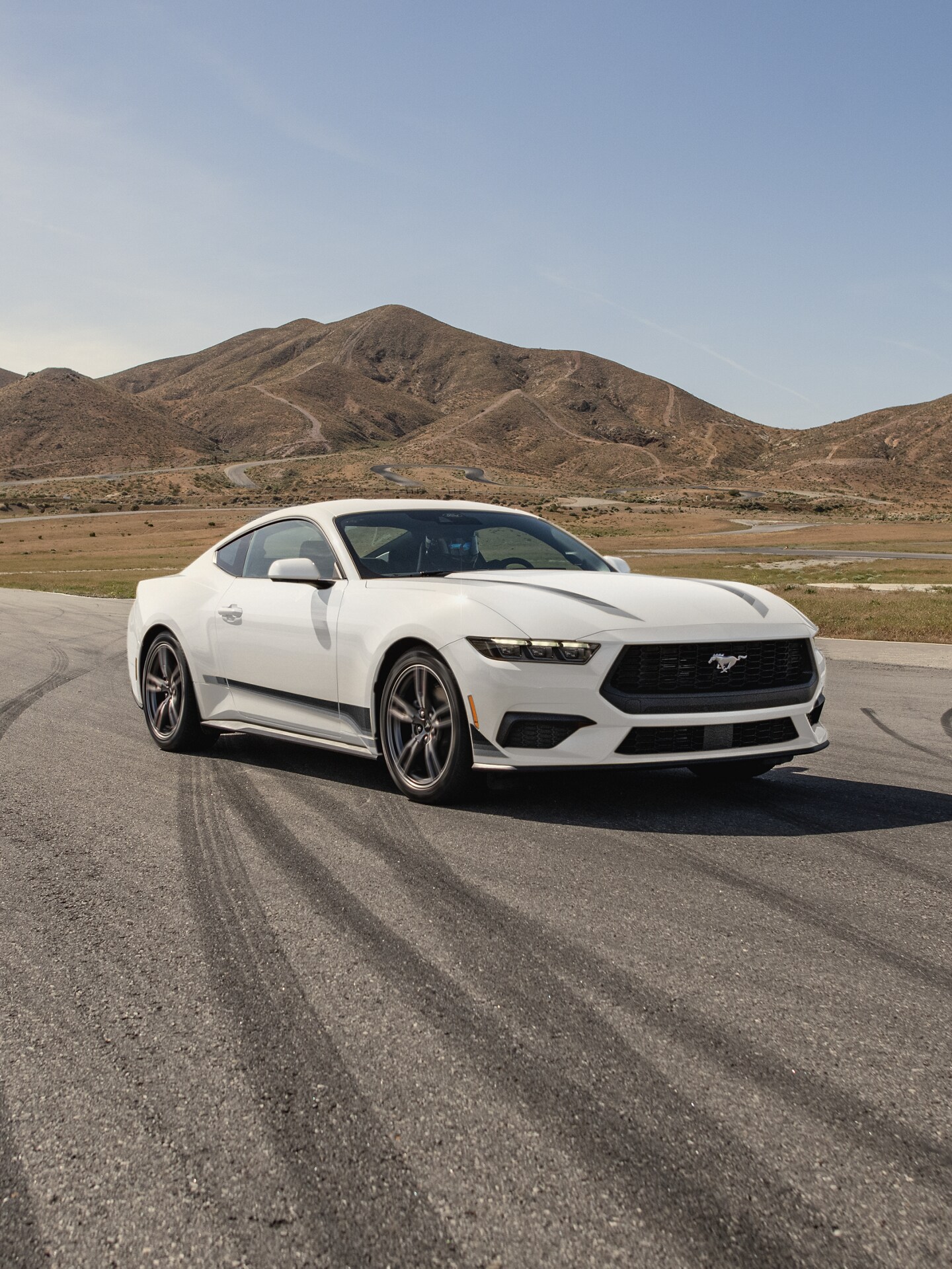 A 2025 Ford Mustang® parked on an asphalt track with a mountain in the background