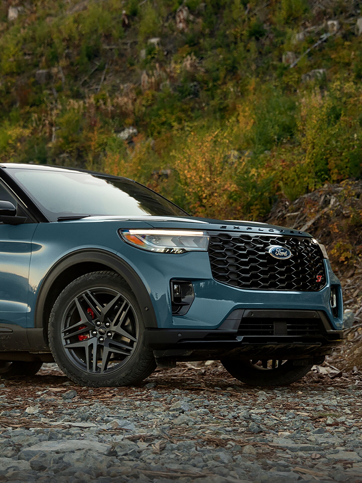 A 2025 Ford Explorer® on a rocky trail with a grass-covered hillside in the background