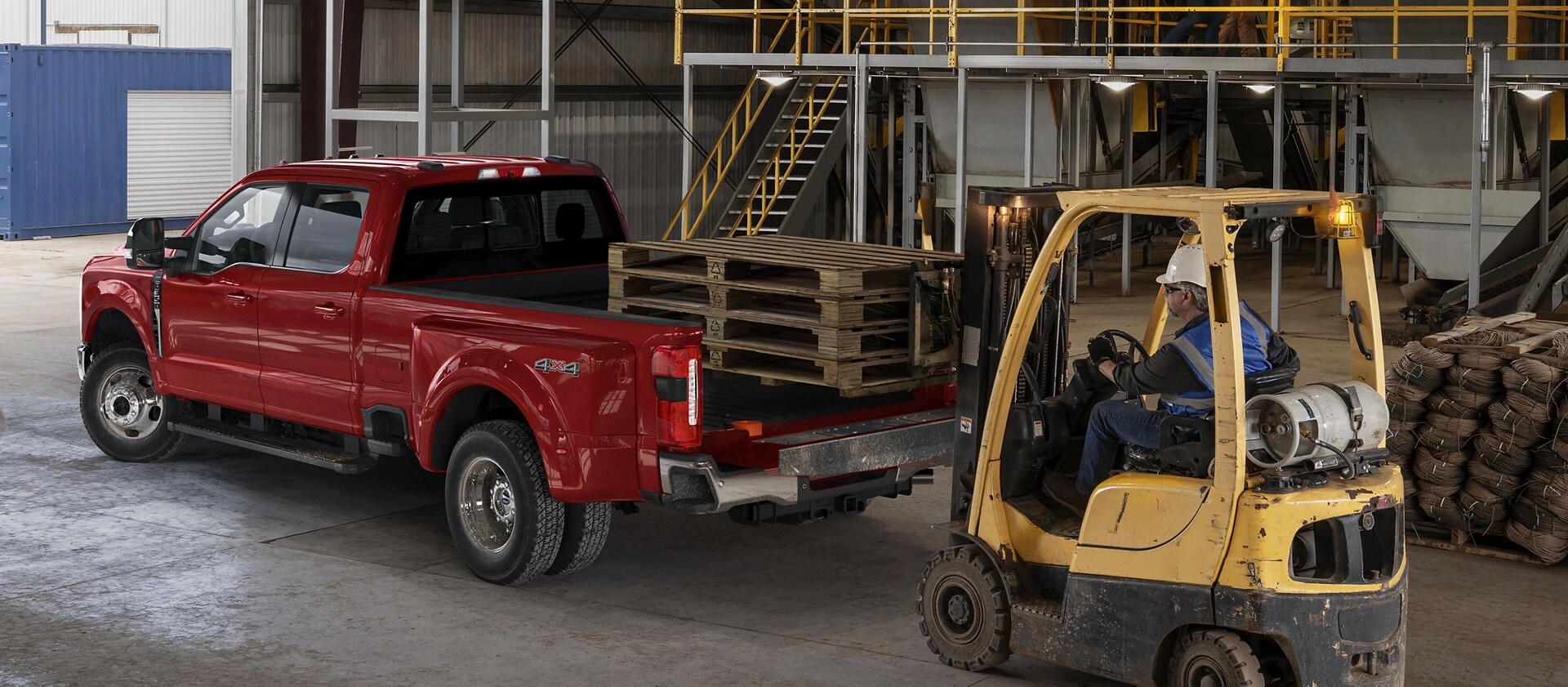 Fork lift loading wooden pallets into the bed of a Ford Super Duty Truck