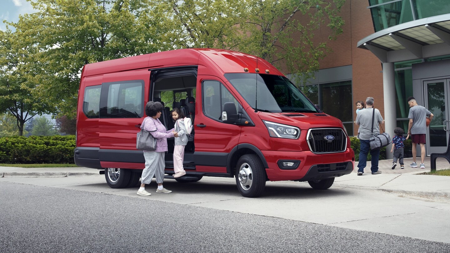 A woman helping a young girl out of a 2025 Ford Transit® van