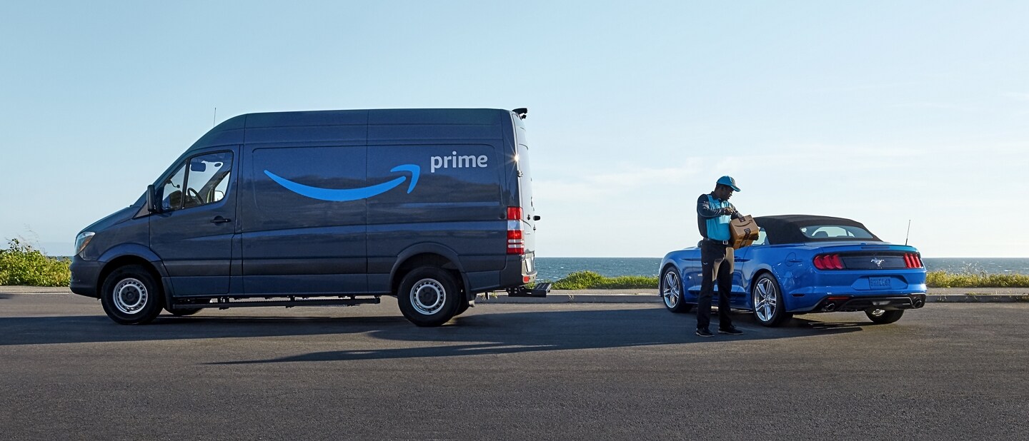 Amazon Prime delivery truck placing package in a Ford Mustang