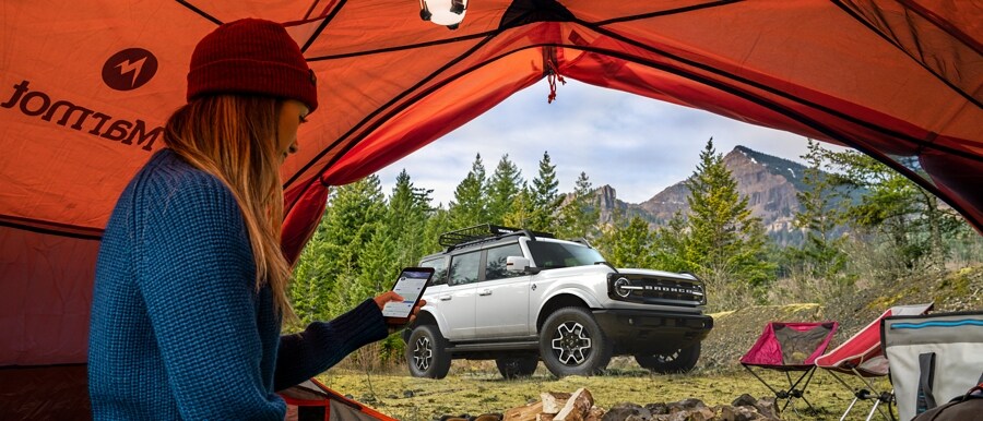 2021 Ford® Bronco four door Outer Banks seen through a tent where a woman is camping
