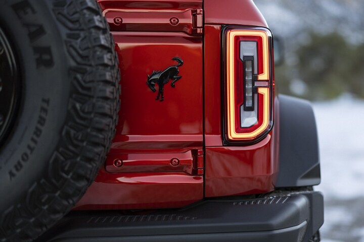 Primer plano de los faros traseros y el logo de una Ford Bronco® Wildtrak® 2023 en Race Red