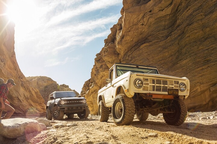 Una Ford Bronco® Badlands® 2023 de dos puertas y una Ford Bronco® de los 60 estacionadas en un cañón