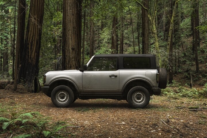 Una Ford Bronco® Base 2023 de dos puertas en Iconic Silver estacionada en un bosque