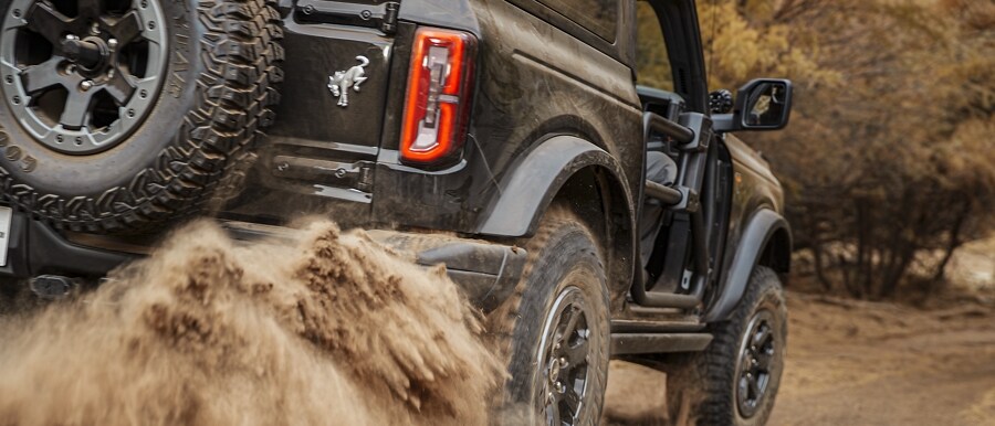 Una Ford Bronco® Base 2023 de dos puertas en Shadow Black andando por un camino de tierra