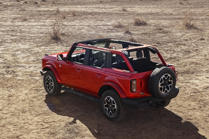 Una Ford Bronco® Outer Banks® 2023 de cuatro puertas en Hot Pepper Red estacionada en el desierto sin techo ni puertas