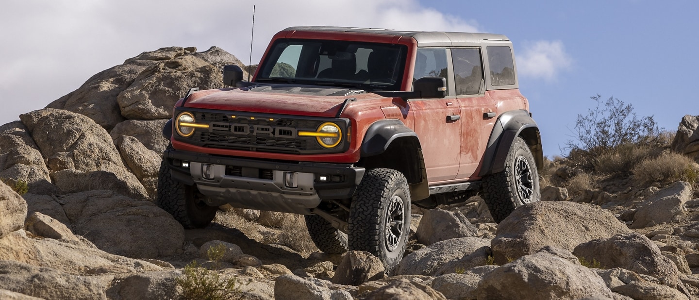 Two-door 2023 Ford Bronco® Badlands® in Shadow Black with available modular front bumper being driven on rocks