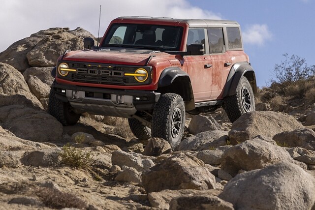 Una Ford Bronco® Badlands® 2023 de dos puertas en Shadow Black con defensa delantera modular disponible andando sobre las rocas