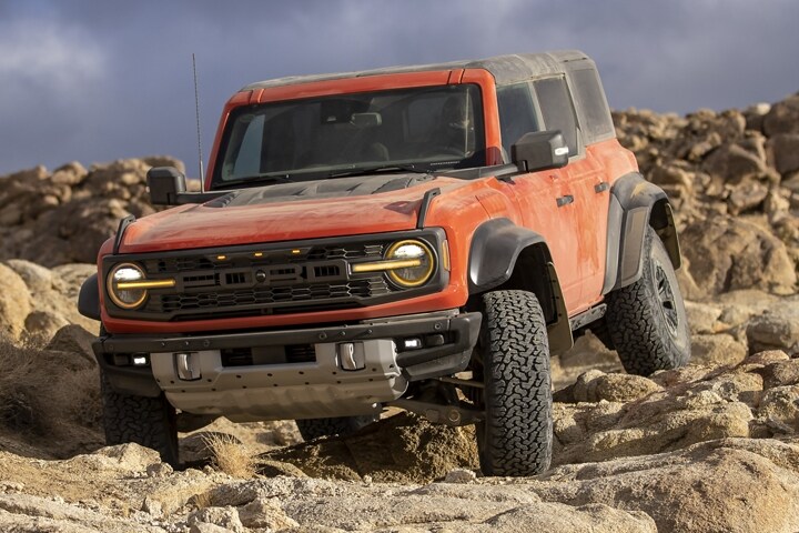 Se muestra una Ford Bronco® Raptor® 2023 de cuatro puertas en Hot Pepper Red andando por las rocas