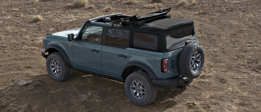Se muestra el modelo Ford Bronco® Badlands® 2023 de cuatro puertas en Azure Gray con techo blando abierto por la mitad