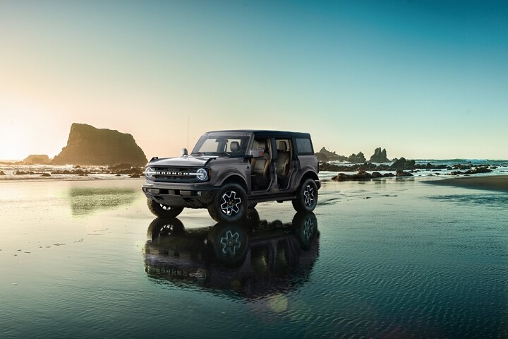 Una Ford Bronco® Outer Banks® 2023 de cuatro puertas en Carbonized Gray estacionada sobre la costa