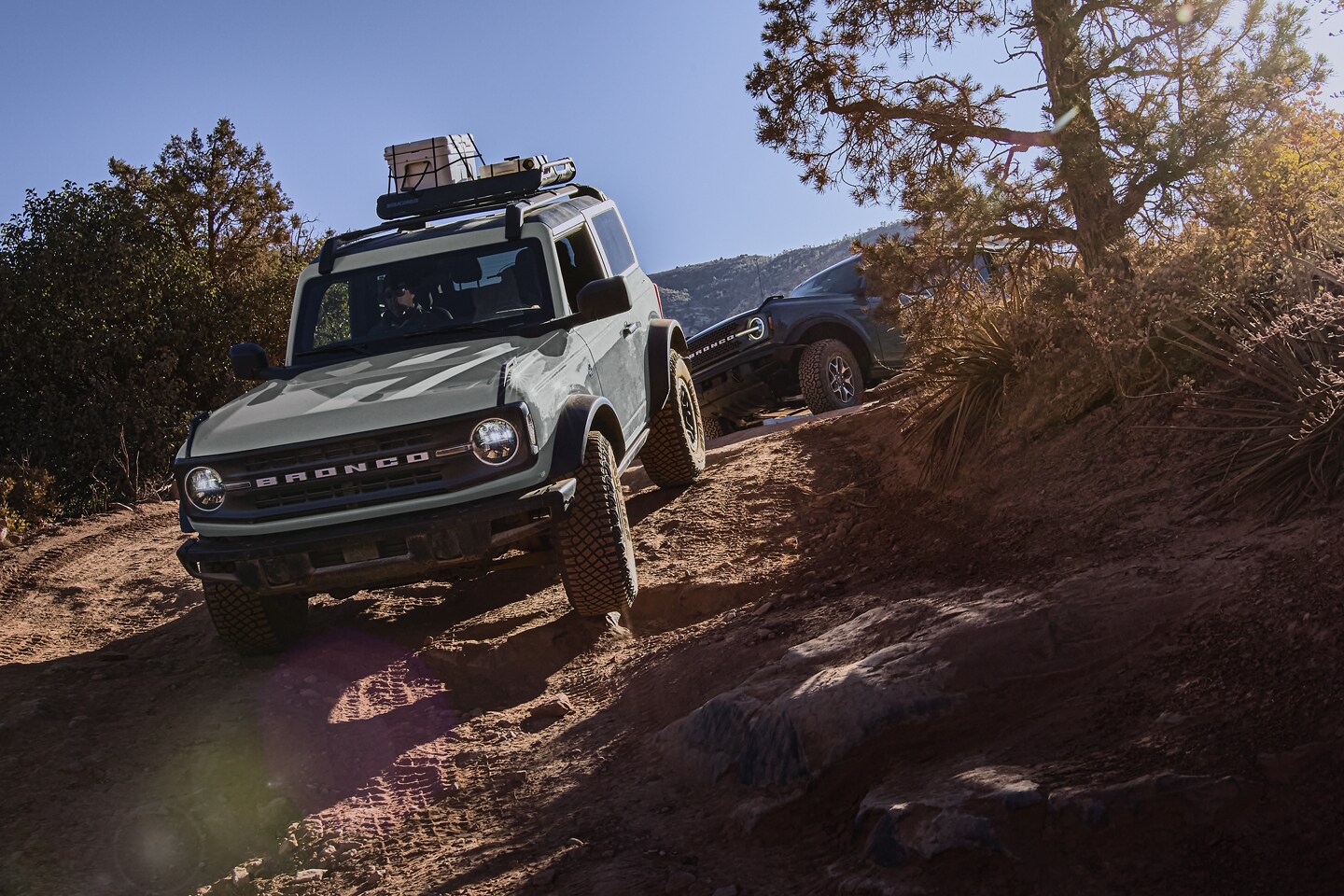 Una Ford Bronco® Black Diamond® 2023 de dos puertas en Cactus Gray andando por un sendero con otra Bronco detrás