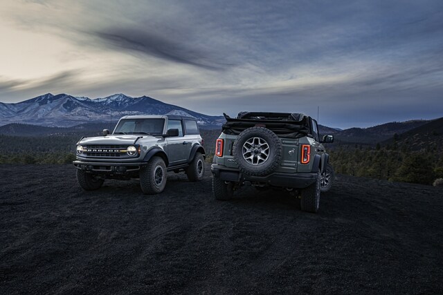 A 2023 Bronco® two-door hardtop and four-door soft top Black Diamond® parked at dusk in the mountains