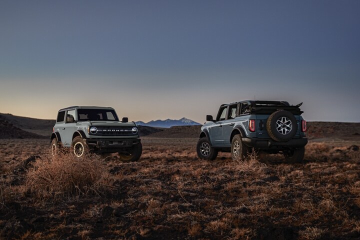 Una Ford Bronco® 2023 en Cactus Gray y una Badlands® 2023 en Azure Gray estacionada en el desierto