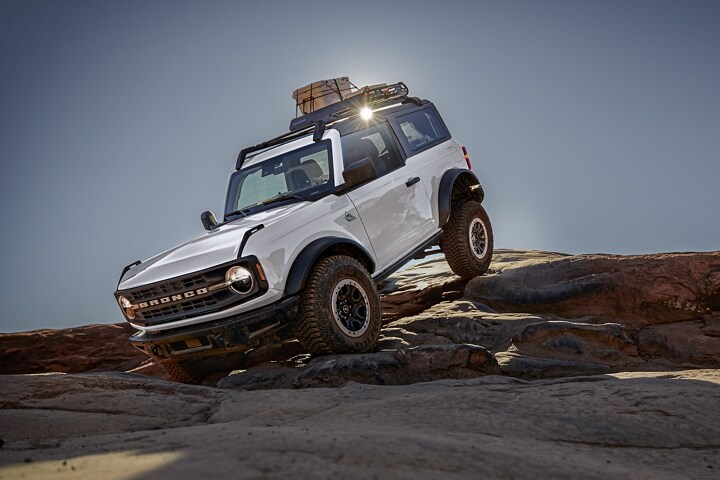 Two-door 2023 Ford Bronco® Black Diamond® in Oxford White being driven on rough terrain