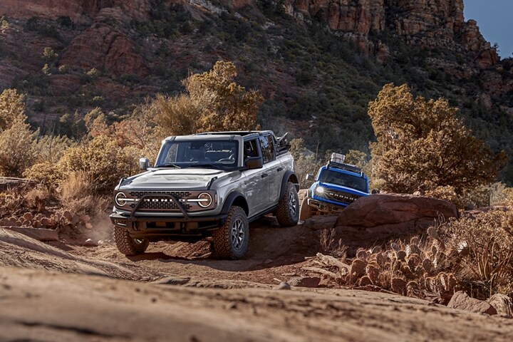 Una Ford Bronco® Badlands® 2023 de cuatro puertas y una Black Diamond® 2022 de dos puertas saliendo de un cañón