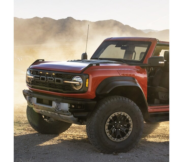 A 2023 Ford Bronco® Raptor® model in Code Orange Red driving off-road