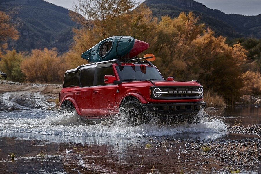 A four-door 2024 Ford Bronco® SUV with aftermarket, roof-mounted Yakima® JayLow kayak carrier