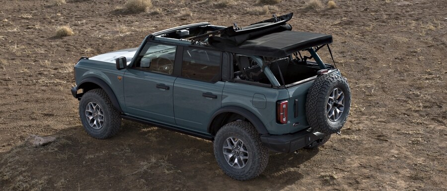 Four-door 2024 Ford Bronco® Badlands® model shown in Azure Gray with soft-top roof half open and rear panel removed