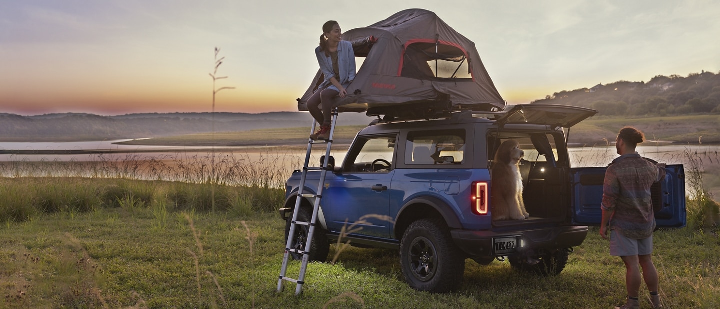 A 2024 Ford Bronco® Badlands® in Velocity Blue with a rooftop tent and two campers