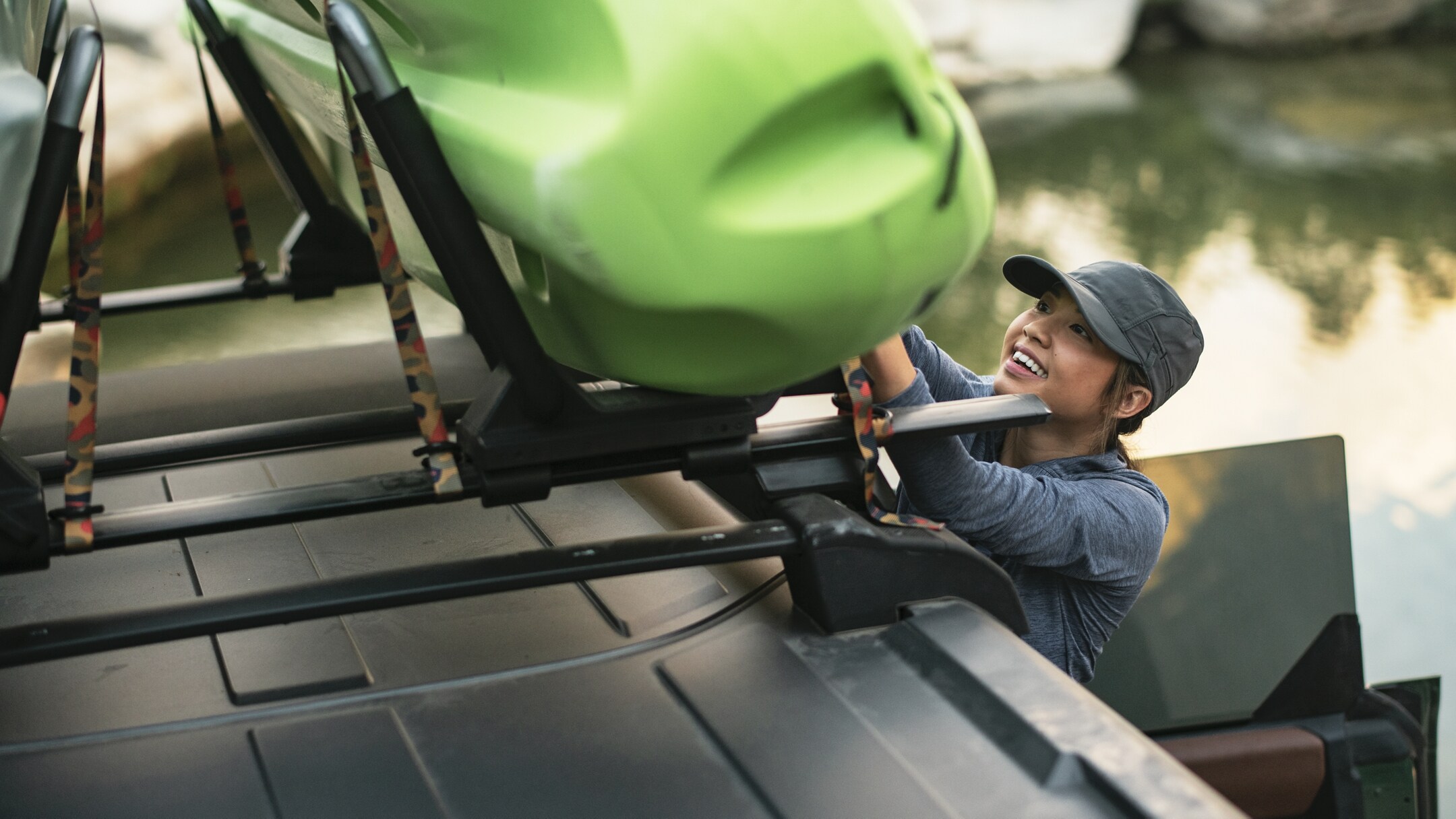 Woman attaching a large canoe to the top of the roof rack of a Ford Bronco Heritage Limited Edtion