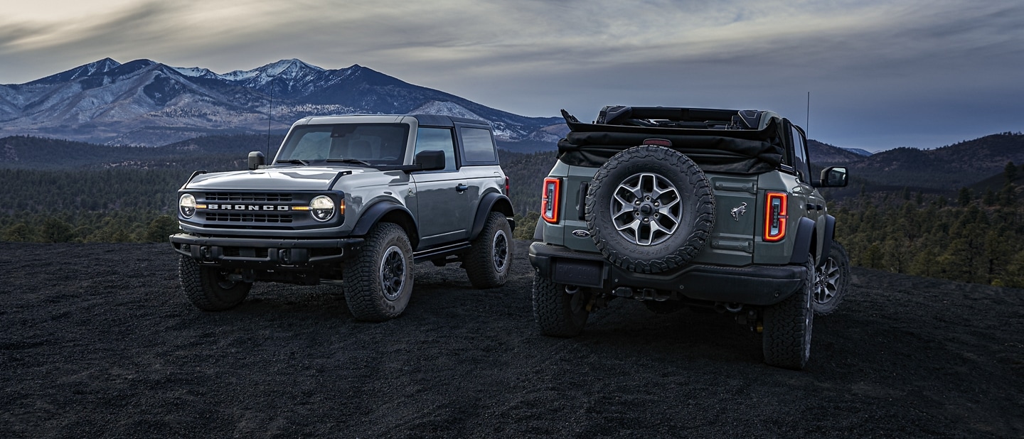 A 2024 Ford Bronco® two-door hardtop and four-door soft top Black Diamond™ parked at dusk in the mountains