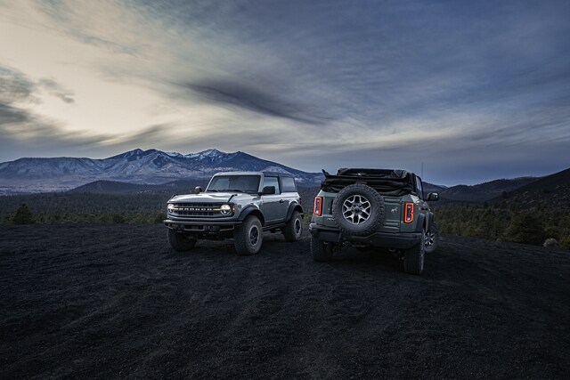 A 2024 Ford Bronco® two-door hardtop and four-door soft top Black Diamond™ parked at dusk in the mountains