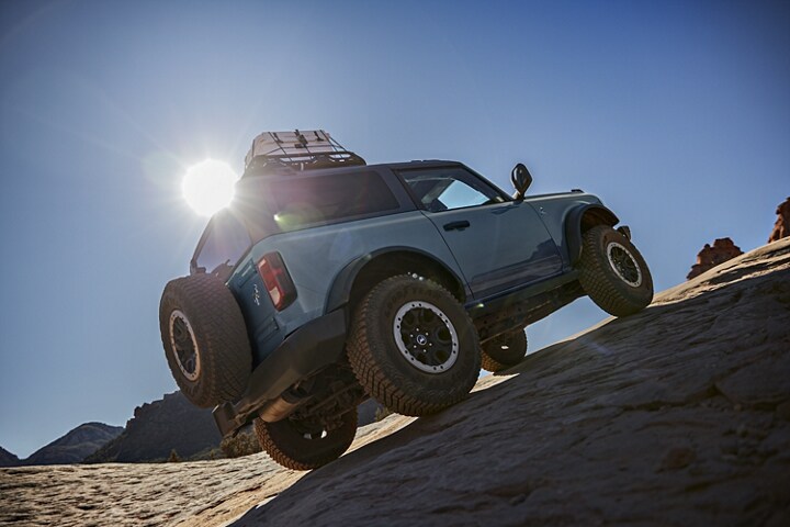 Two-door 2024 Ford Bronco® Black Diamond™ in Azure Gray climbing rugged terrain