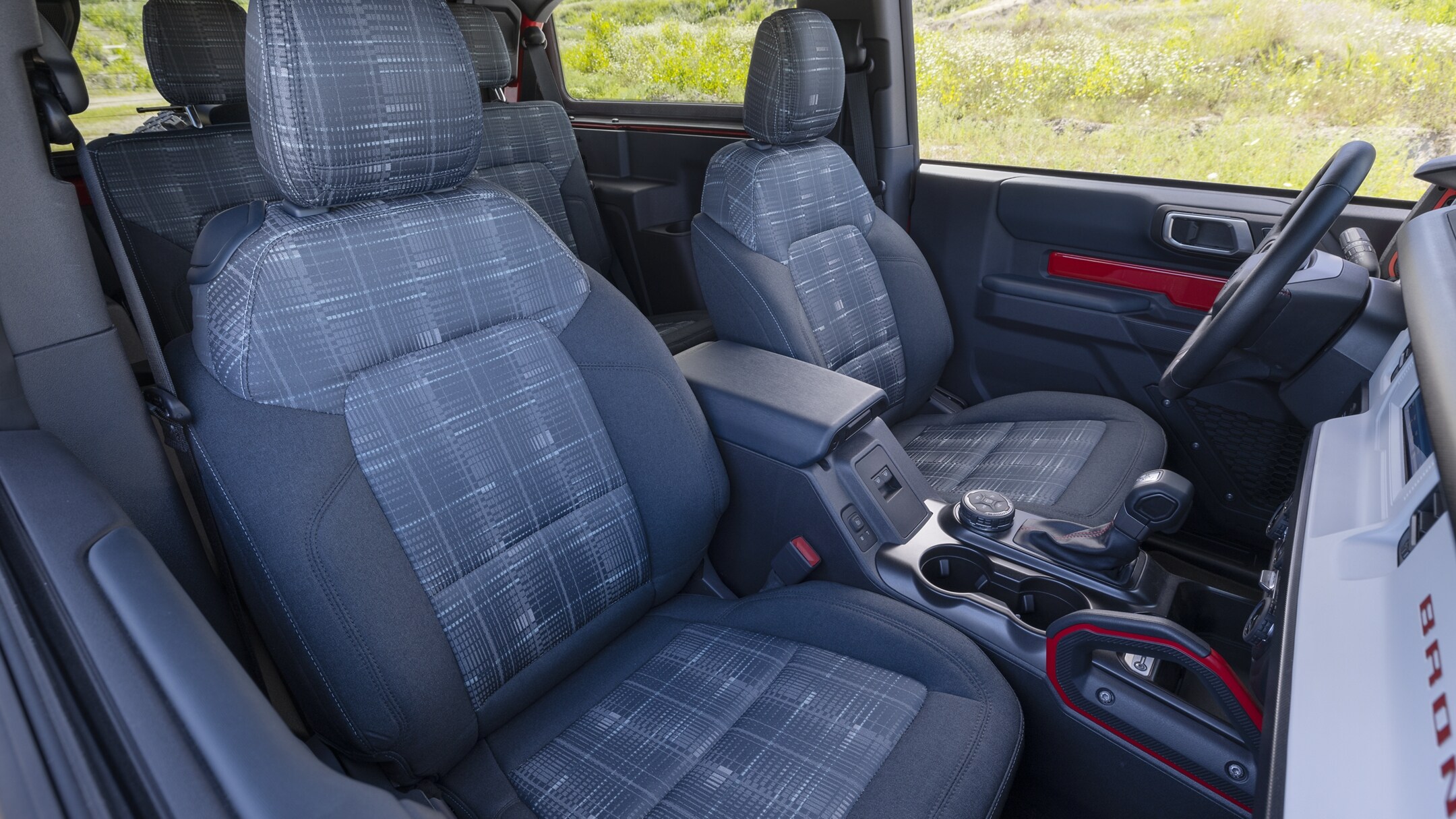 4 person seating with cloth plaid interior, red accent trim and a manuel gear tramission shifter