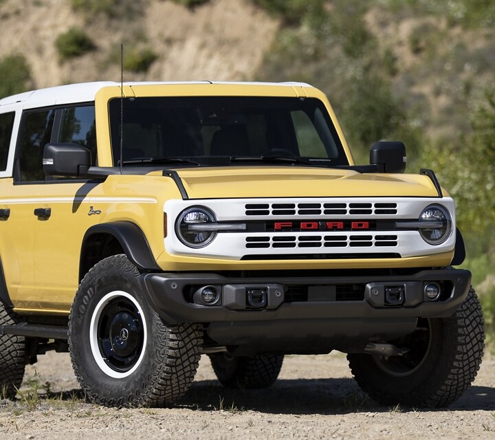 A 2024 Ford Bronco® Heritage Limited Edition in Yellowstone Metallic parked next to a lake