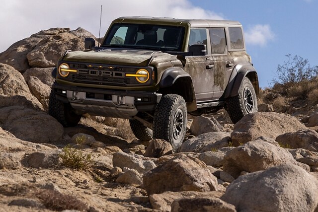 2024 Ford Bronco® Raptor® in Shelter Green climbing over rocks in a desert terrain