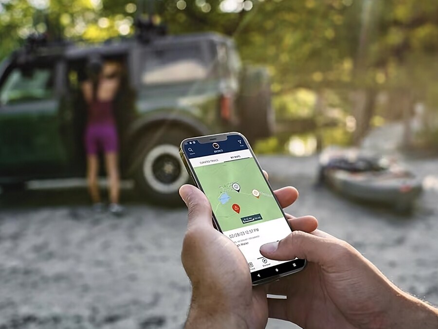 Close-up of a smartphone showing the app working with a 2024 Ford Bronco® in the background