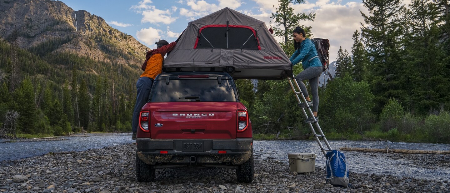 Two people setting up camp on top of a 2021 Ford Bronco Sport