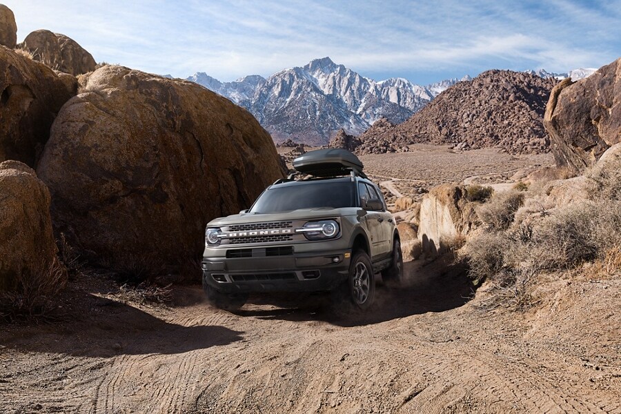 Una SUV Ford Bronco® Sport 2023 circulando por un camino de tierra con montañas en segundo plano