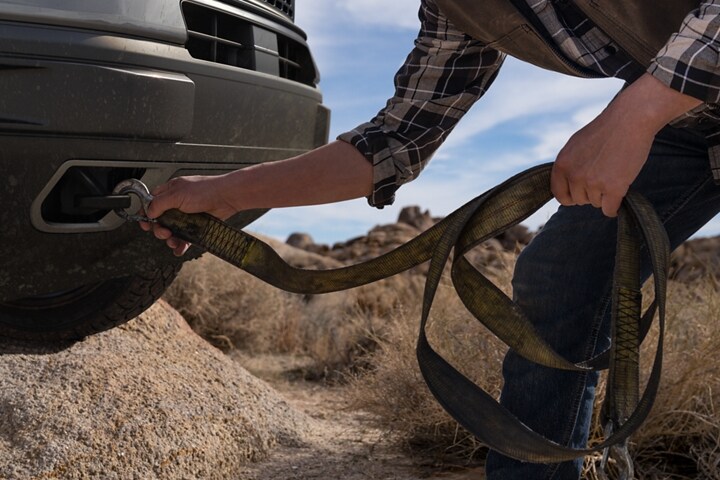 Man hooking up a tow strap to the front of his Ford Bronco® Sport SUV