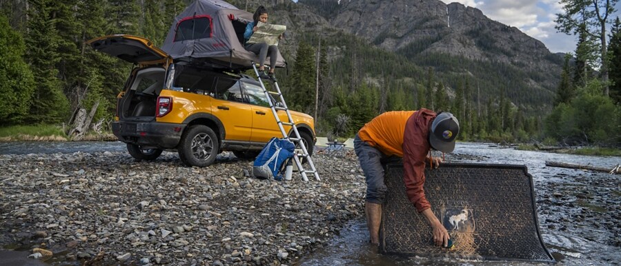 Hombre lavando un tapete de vehículo en el río