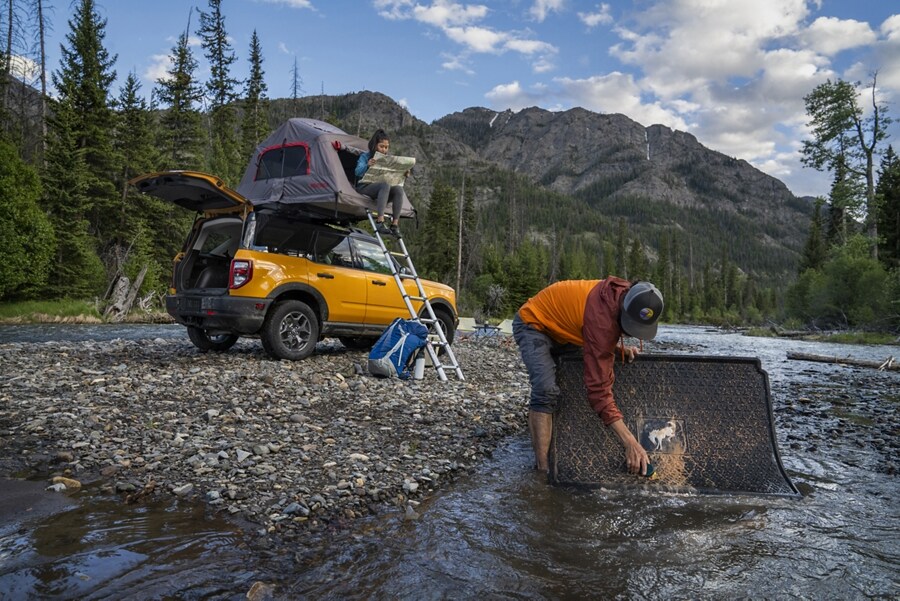Man scrubbing a rubberized mat in the river