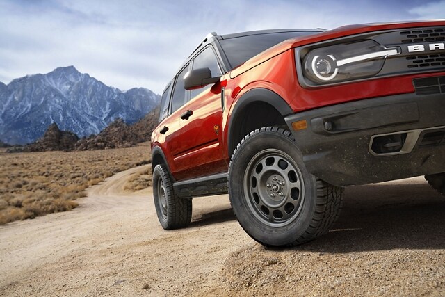 Imagen de tres cuartos de la SUV Ford Bronco® Sport 2023 estacionada en un camino de tierra con montañas de fondo