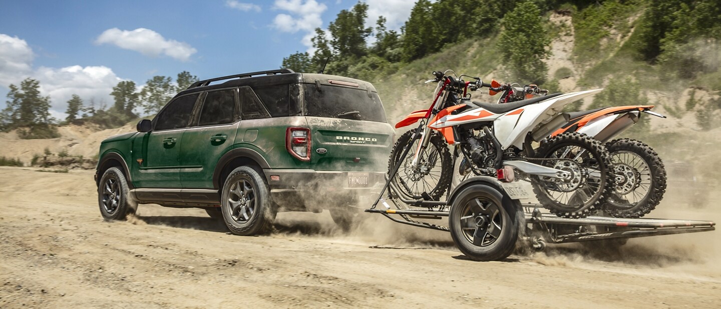 Una Ford Bronco® Sport 2023 remolcando un tráiler con motocicletas encima