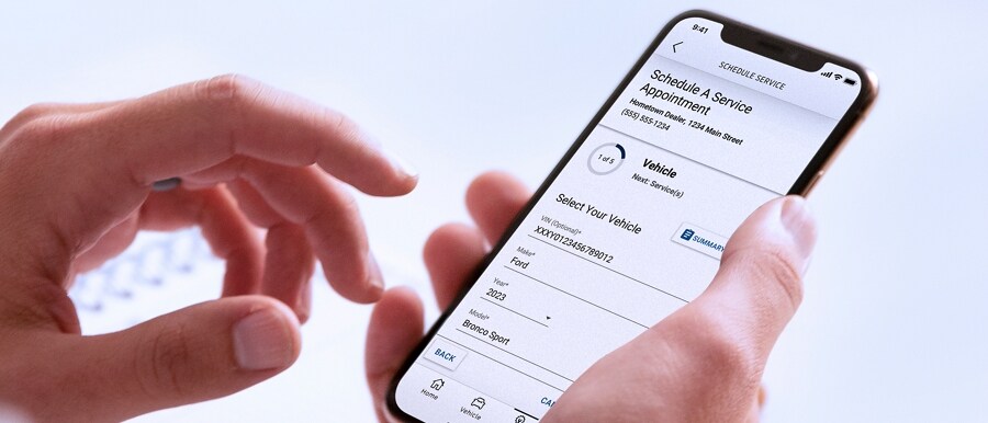 Un hombre sosteniendo un smartphone que muestra el menú Programar Servicio en la Aplicación FordPass®