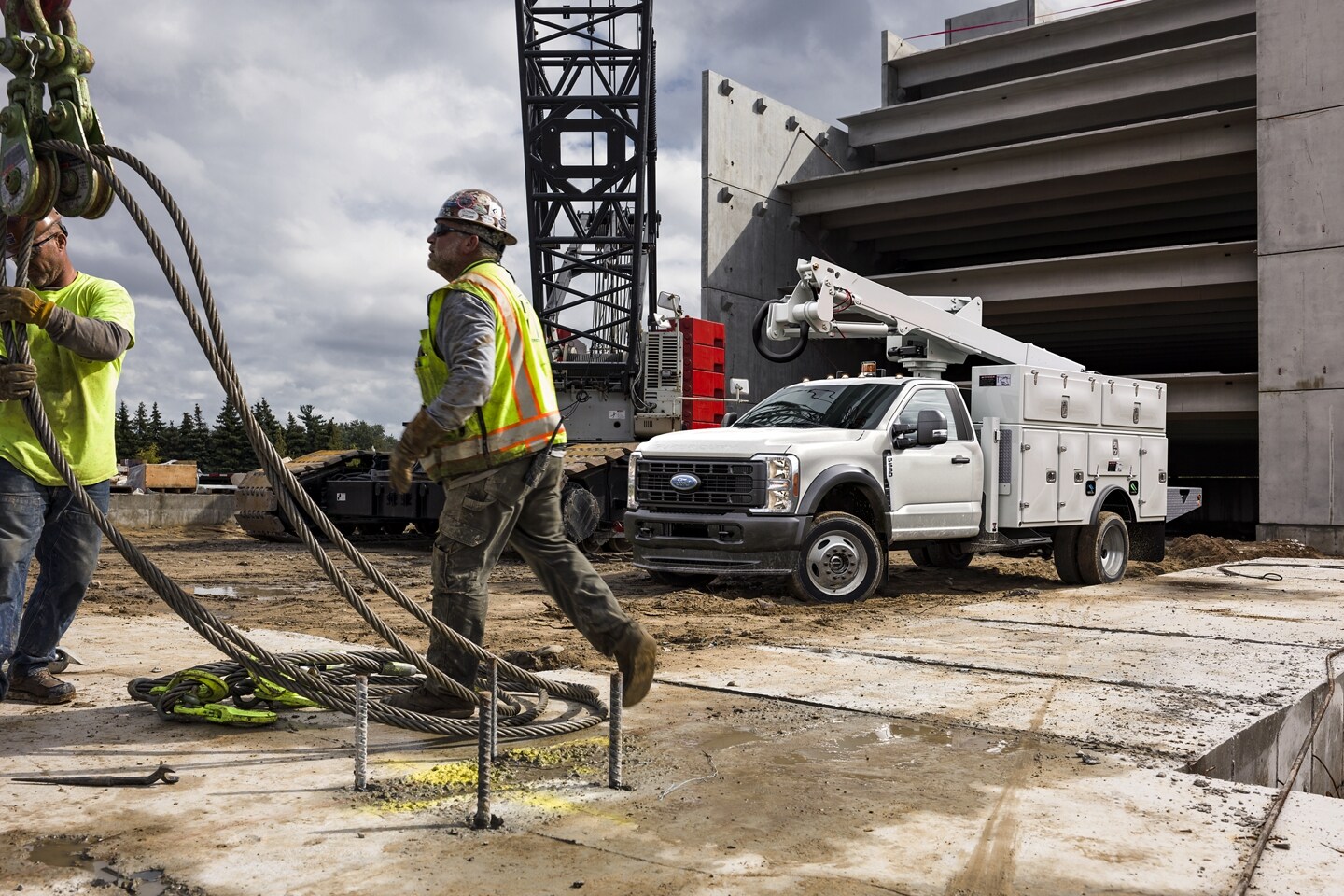 Contractors bringing a heavy payload to a White 2023 Ford F-550 Chassis Cab equipped with heavy duty small crane.