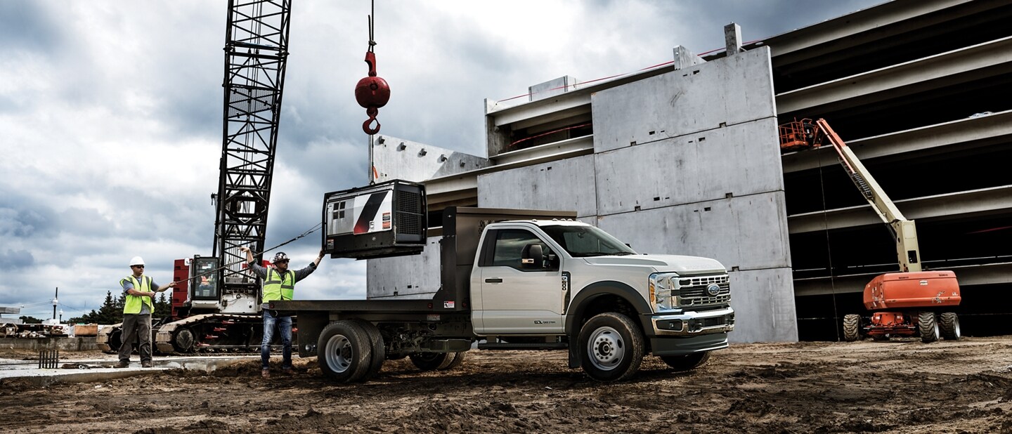 2023 Ford Super Duty® Chassis Cab with flatbed body with equipment being loaded on the truck bed