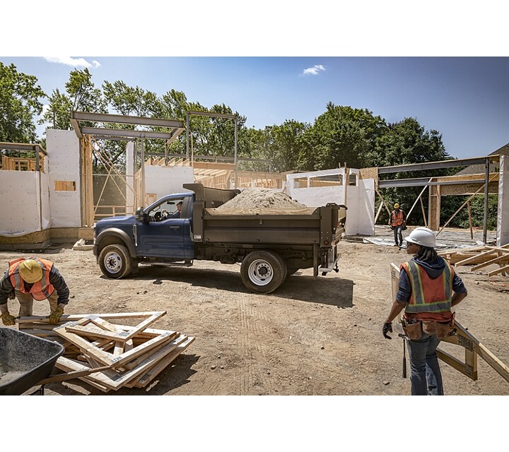 2023 Ford Super Duty® parked at a building site with dump upfit and a bed full of dirt