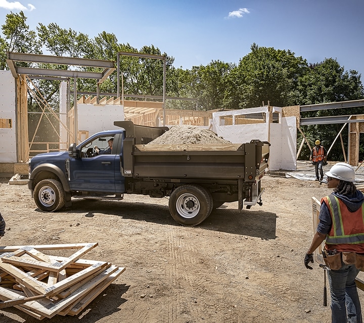 Una Ford Super Duty® 2023 estacionada en un sitio de construcción con mejora de volquete y la plataforma llena de material