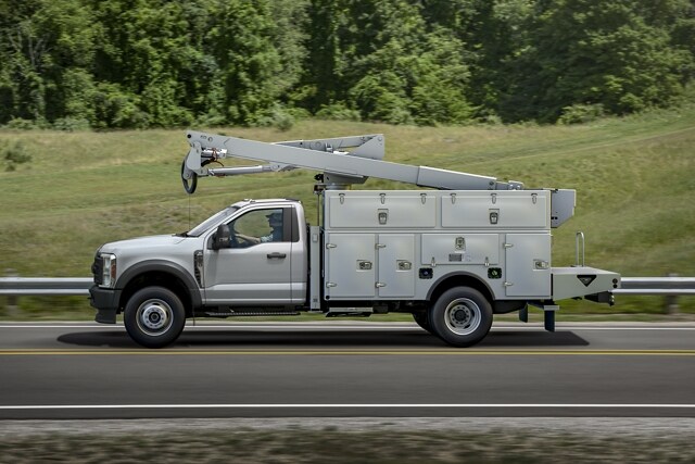 Side view of 2023 Ford Super Duty® Chassis Cab with upfit being driven on the road near grass and trees