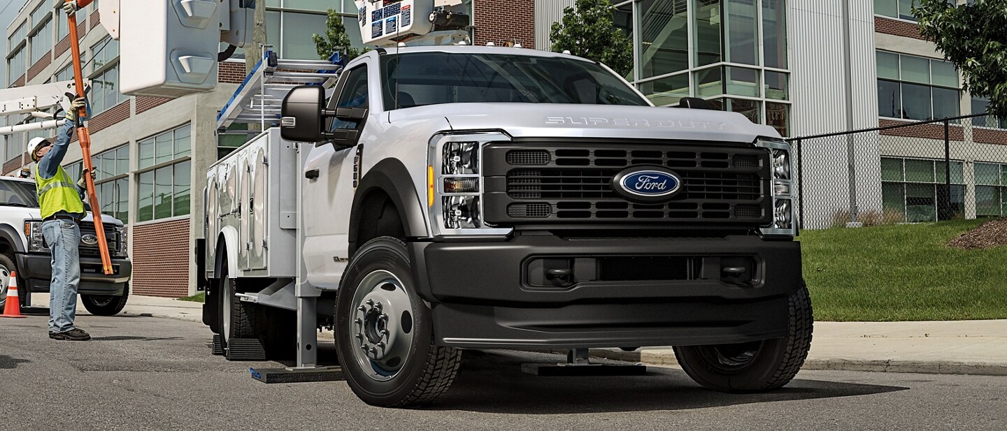 Trabajadores moviendo maquinaria cerca de una Ford Super Duty® Chassis Cab 2023 con mejoras en un lugar de trabajo